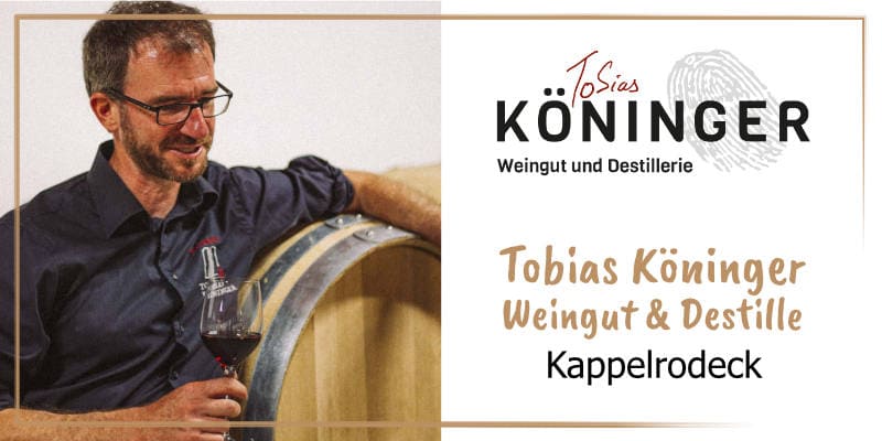 Auf der goldbraun gerahmten WasRegionales-Markenkachel lehnt Tobia sKoeninger mit einem Glas Rotwein an einem Weinfass aus Holz; das Logo von Tobias Köninger Weingut und Destille; darunter der Schriftzug Tobias Koeninger Weingut und Destille, Kappelrodeck