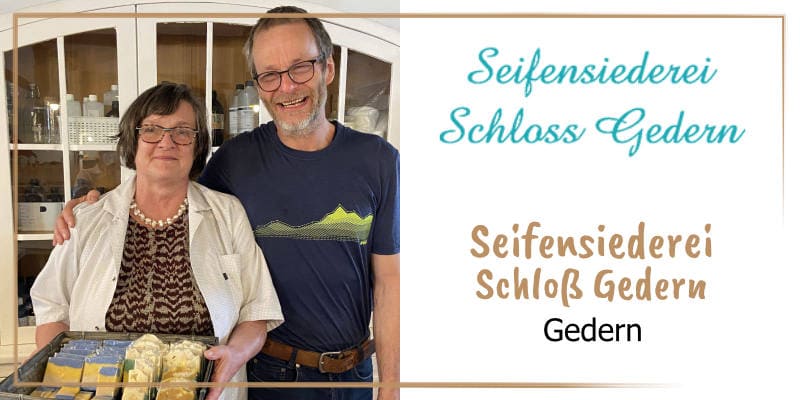 Auf der goldbraun gerahmten WasRegionales-Markenkachel Berndaotte Boehm und ihr Mann schauen freundlich in die Kamera, stehen vor einer Verkaufsvitrine in ihrer Seifensiederei und praesentieren eine Seifenauswahl im Koerbchen; das Logo mit dem Unternehmen