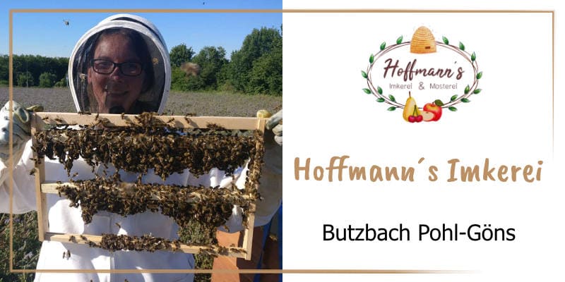 Auf der goldbraun gerahmten WasRegionales-Markenkachel Melanie Hoffmann in Imkerkleidung eine halbgefuellte Honigwabe mit Bienen hochhaltend; das Logo von Hoffmanns Imkerei und Mosterei; darunter der Schriftzug Hoffmanns imkerei, Butzbach Pohl-Goens