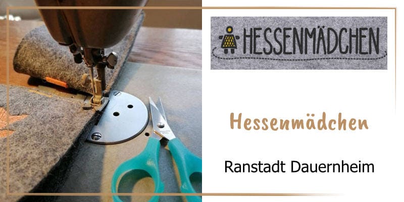 Auf der goldbraun gerahmten WasRegionales-Markenkachel Fotoausschnitt Filz in der Naehmaschine eingespannt und danebenliegende Schere; das Logo von Hessenmaedchen; darunter der Schriftzug Hessenmaedchen, Ranstadt Dauernheim