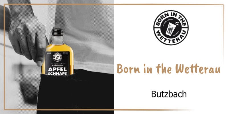 Auf der goldbraun gerahmten WasRegionales-Markenkachel Ein schwarz-weiß Fotoausschnitt eines jungen Mannes helles Shirt, dunkle Hose mit der Hand an einer Flachmann Flasche Born in the Wetterau Apfelschnaps in der Hosentasche; das Logo von Born in the Wet